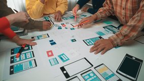 A diverse team engages in a dynamic brainstorming session for app development, surrounded by sketches and prototypes, showcasing collaboration and creativity in a modern workspace. SACTR - Powered by Shutterstock - Get 15% off with code: PIKWIZARD15