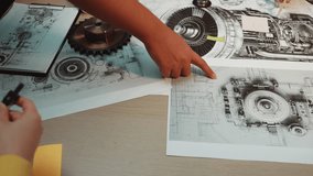 An engineer analyzes detailed technical drawings and schematics related to machinery parts, showcasing creativity and precision in a collaborative workspace setting. SACTR - Powered by Shutterstock - Get 15% off with code: PIKWIZARD15