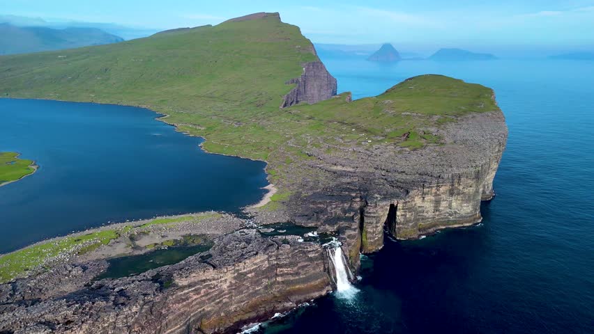Explore the stunning coastal cliffs of the Faroe Islands, where cascading waterfalls meet serene blue waters. This remote paradise captivates with its dramatic landscapes, Sorvagsvatn lake, Vagar