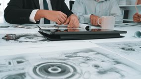 A group of business professionals collaborates over design blueprints and project plans in a modern office setting, showcasing teamwork and innovative ideas. SACTR - Powered by Shutterstock - Get 15% off with code: PIKWIZARD15