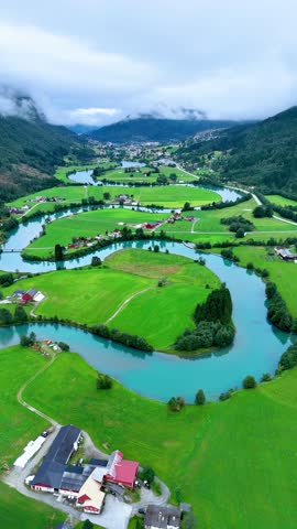 Explore the breathtaking landscape of Stryn, Norway, featuring winding rivers, green pastures, and serene mountains. A picturesque view capturing the tranquility of nature in this stunning region.