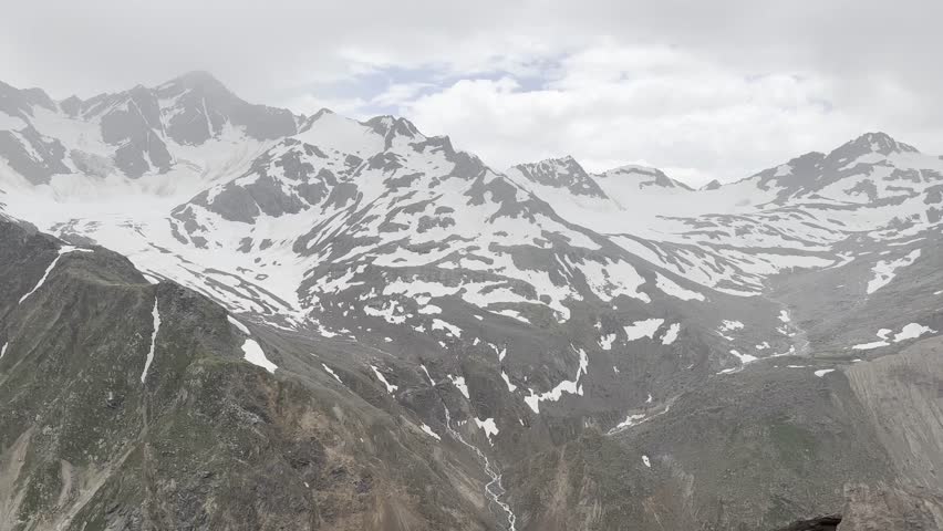Majestic Snow-Capped Mountains Under Cloudy Sky During Summer Day