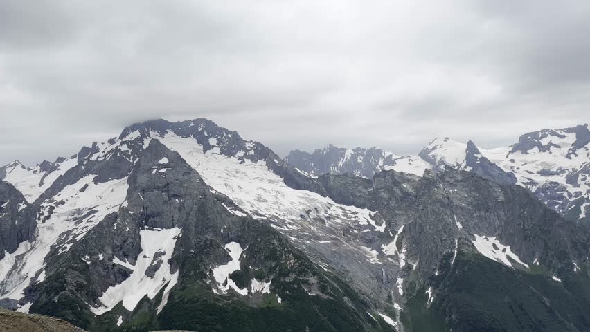 Scenic Mountain Landscape With Snow and Cloudy Sky During Summer