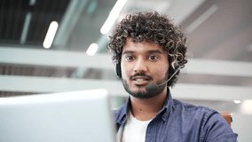 Young smiling male corporate operator in headset working in customer support service on helpline telesale talking using laptop in business office. Agent of call center advises client online. Close up - Powered by Shutterstock - Get 15% off with code: PIKWIZARD15