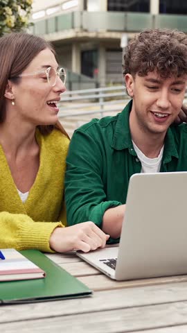 Two students working together on a laptop, studying and learning for University exams