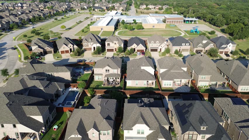 Elementary School in Lantana, Texas with track and field, playground, two story houses, forested land reserved for future development. Highlights educational infrastructure, suburban planning. USA