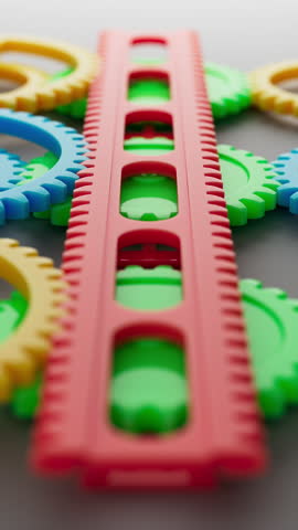 Vivid 3D loop of colorful plastic gears and racks in red, yellow, green, and blue, intermeshing and rotating in synchronized motion to create a playful, smooth, and endlessly cycling animation scene.