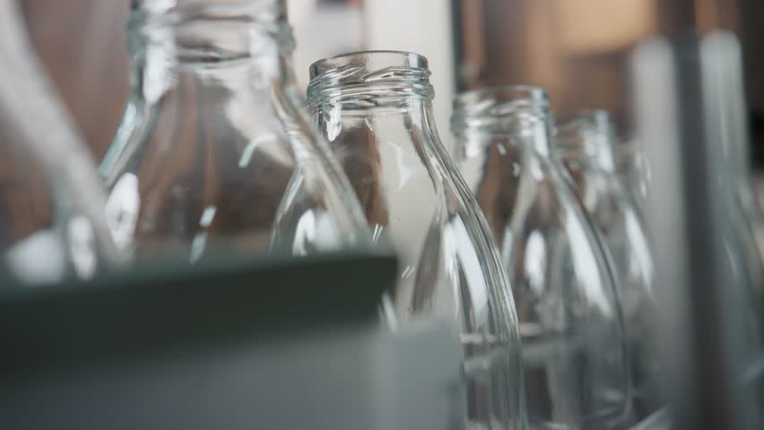 Empty glass bottles are moving on a conveyor belt, ready to be filled with milk or yogurt in a dairy production line, ensuring hygiene and efficiency in industrial food processing