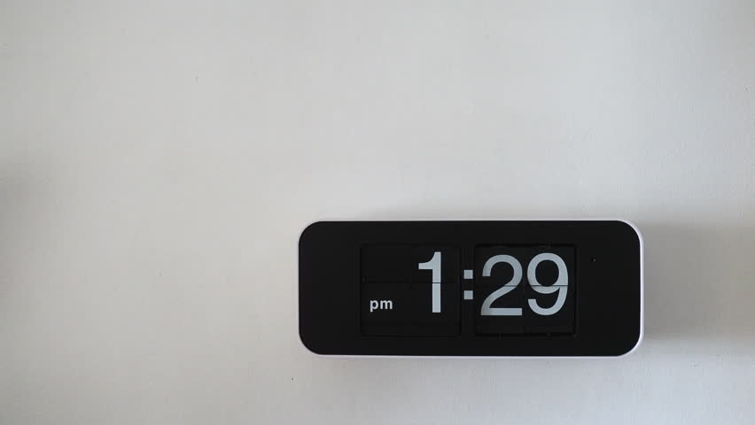 Flip wall clock with black face hanging on a white wall background
