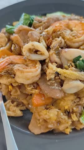 Savory Seafood Dish: A mouthwatering close-up of stir-fried noodles, generously laden with succulent shrimp, tender calamari, and fresh vegetables, a culinary masterpiece.