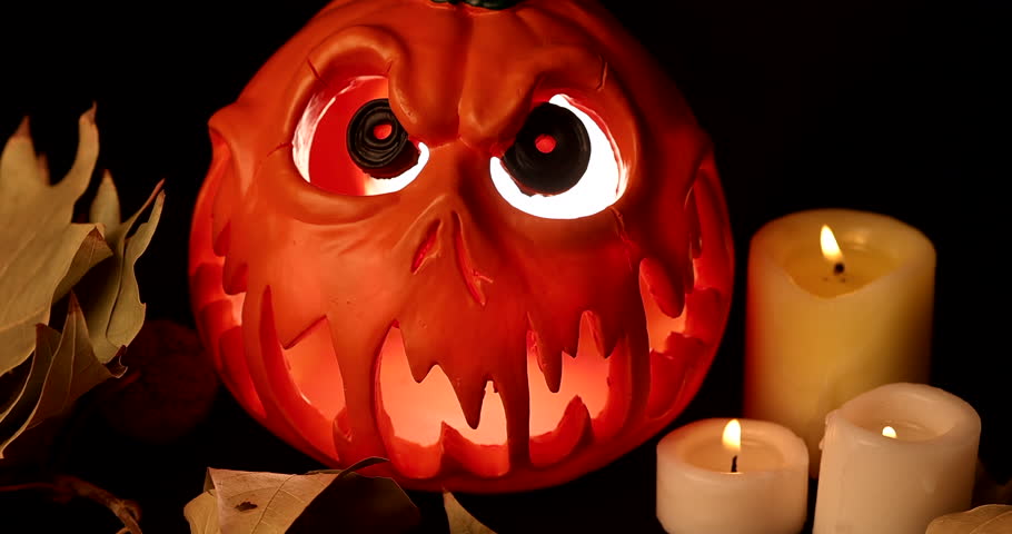 Eerie pumpkin face glowing inside heavy fog, surrounded by dry leaves and branches on black scene.