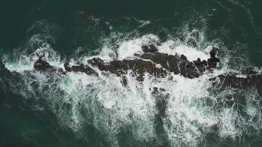 Aerial top down view of waves splashing into rocks in the sea, super slow motion - Travel and nature concepts, background ready HD video
