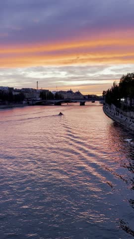 Romantic evening in Paris with a boat gliding down the Seine, swans soaring across the sky, and a glowing orange-pink sunset painting the horizon