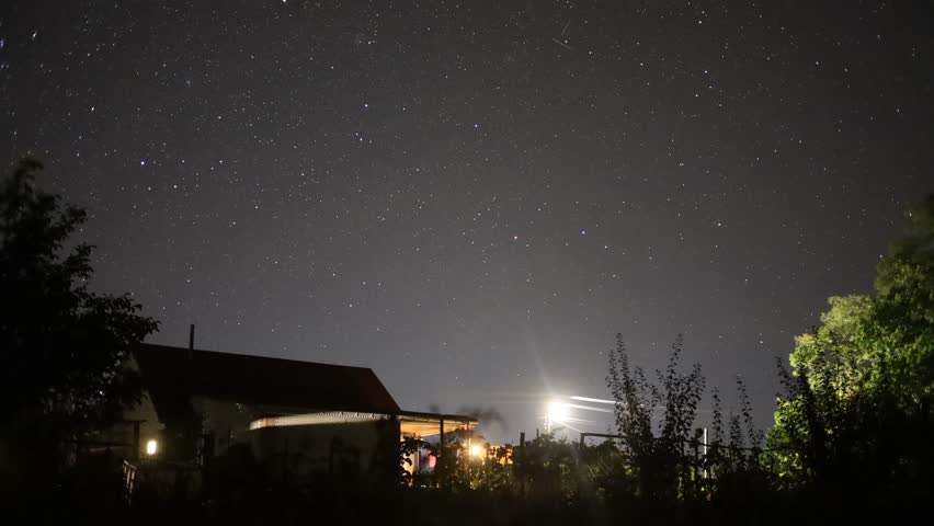 Stars moving above a country house at night