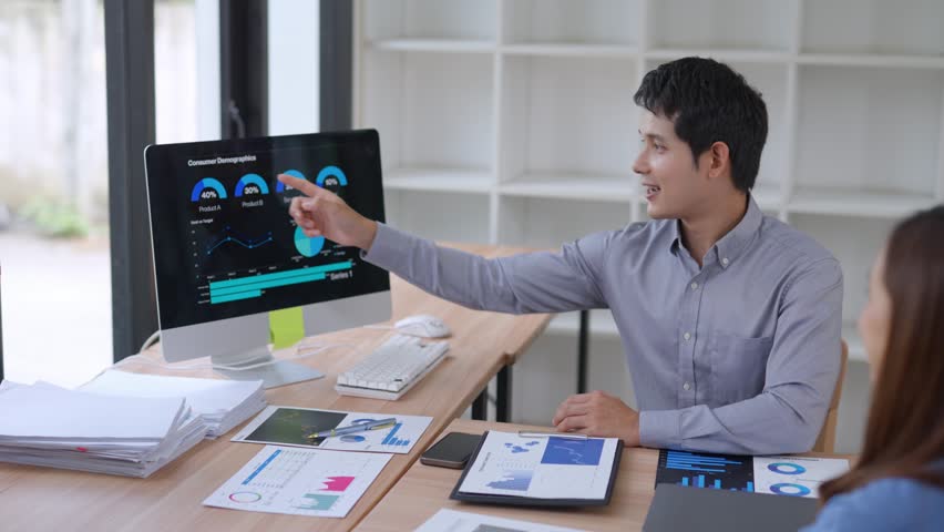 Professional businessman presenting performance charts to female colleague, analyzing digital data while collaborating on marketing strategy in modern, bright office workspace - Powered by Shutterstock - Get 15% off with code: PIKWIZARD15