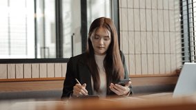 Professional businesswoman calculating financial data while working on documents, using smartphone at sleek office desk, embodying modern business productivity and technological efficiency - Powered by Shutterstock - Get 15% off with code: PIKWIZARD15