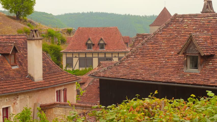 View of a rustic medieval street in Saint-Cirq Lapopie, France, featuring traditional stone houses and countryside charm.