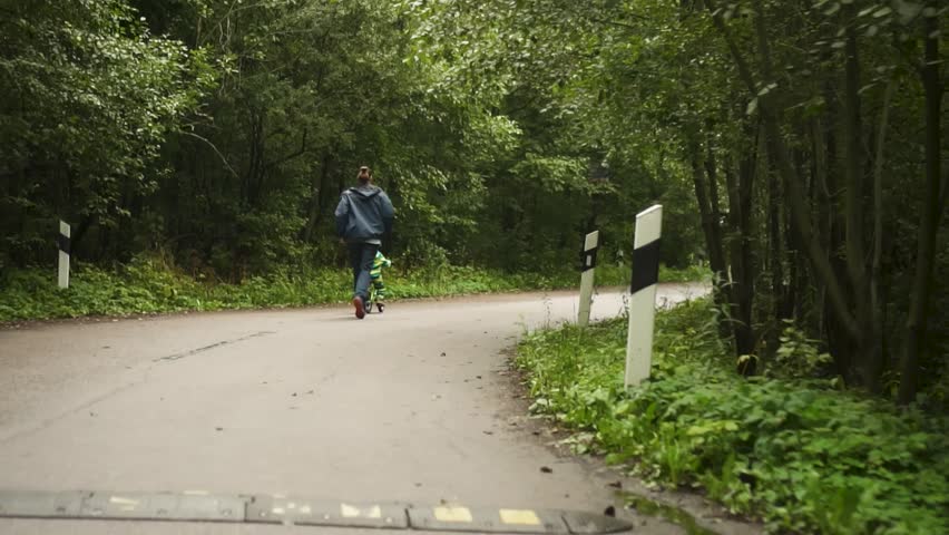 Child wearing safety helmet experiences first bicycle ride while father runs alongside providing security and encouragement during learning.