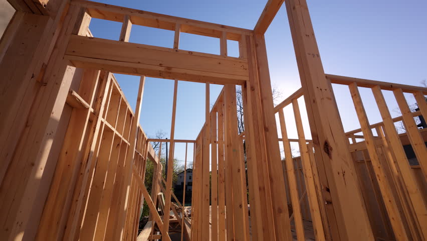 Wooden Beams and posts under clear sky on the construction development site. Construction frame of New House. Dolly in Camera move.