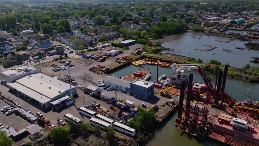 Drone aerial view of the Kill Van Kull waterway with Staten Island and Bayonne shorelines, industrial ports, and distant Manhattan skyline. Maritime shipping route on a clear sunny summer day. ProRes.