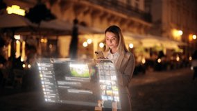 Young woman chatting through a glowing holographic interface on the street at night, concept of augmented reality communication and futuristic technology - Powered by Shutterstock - Get 15% off with code: PIKWIZARD15