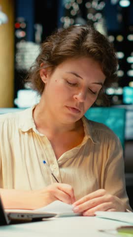 Vertical Video Businesswoman makes mistake in transcribing finance updates on notebook, tearing up the paper sheet and restarting. Discontent impatient worker wanting to finish tasks for the night