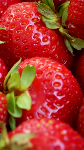 Fresh strawberries with deep red color and juicy texture stacked in wooden crate. Green leaves add contrast. Rustic seasonal harvest, ripe summer berries ready for eating