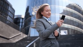 Businesswoman in gray suit smiles while talking on cellphone in urban setting. - Powered by Shutterstock - Get 15% off with code: PIKWIZARD15