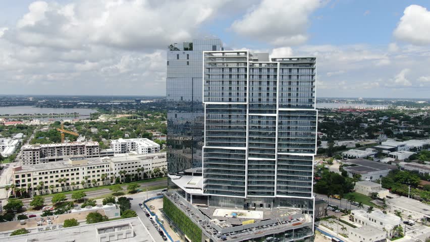 Continuous cruise past sleek glass high-rises by the marina and Intracoastal in West Palm Beach. Parallax of buildings and waterway under bright, sunny conditions.