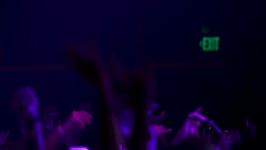 Silhouette of crowd dancing at concert with strobe lights
