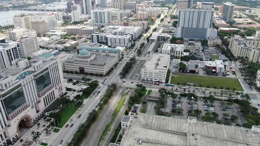 Drone tracks along Quadrille Boulevard with cars, parking, and skyline. Clean daytime shot with parallax.