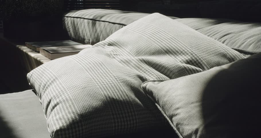 An intimate corner capturing the sunlit coziness on a textured couch with plump cushions, casting intricate shadows. Sunlight Streaming Over Cushions on an Inviting Couch