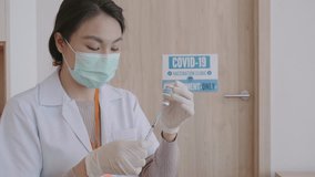 A healthcare worker wearing a mask and gloves prepares for a vaccination appointment in a clinic setting, ensuring safety during the COVID-19 pandemic. - Powered by Shutterstock - Get 15% off with code: PIKWIZARD15