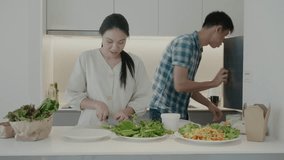 A couple prepares a variety of fresh salads in a modern kitchen. The woman is chopping lettuce while the man is in the background. The colorful ingredients and sleek kitchen setup highlight a healthy  - Powered by Shutterstock - Get 15% off with code: PIKWIZARD15