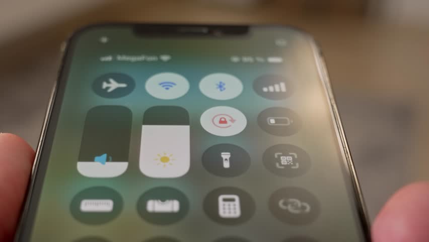 Traveler's hand activating airplane mode on smartphone screen, ensuring connectivity interruption before flight takeoff and following safety regulations