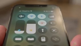 Traveler's hand activating airplane mode on smartphone screen, ensuring connectivity interruption before flight takeoff and following safety regulations - Powered by Shutterstock - Get 15% off with code: PIKWIZARD15