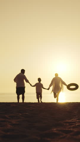 Family time in summer weekend, silhouette of parents and son stretching hands up . People feeling happiness and joy, joyful little child, mother and father resting on sandy beach on seashore in summer