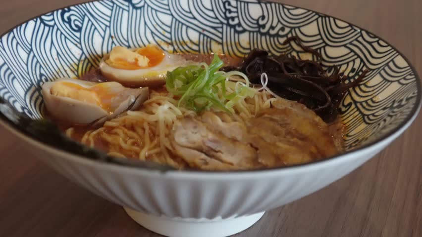 A delicious bowl of Japanese chicken ramen with rich broth, soft-boiled eggs, and fresh vegetables. This top-down view is perfect for themes of Asian cuisine, culinary experiences, and comfort food.