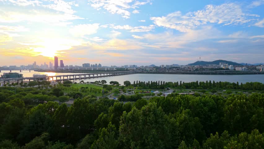 Scenic summer sunset in Seoul with Banpo Bridge and Namsan Tower skyline, sunlight reflecting in Han River