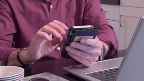 Close-up detail shot of senior man's hands using smartphone in kitchen setting with laptop nearby. Modern technology use and digital communication by mature adults. - Powered by Shutterstock - Get 15% off with code: PIKWIZARD15