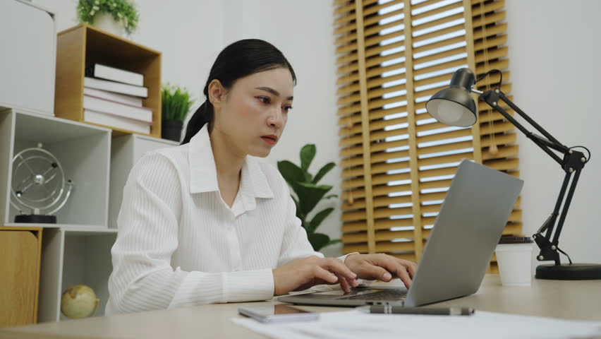 sleepy young woman yawning while working with laptop computer at home office