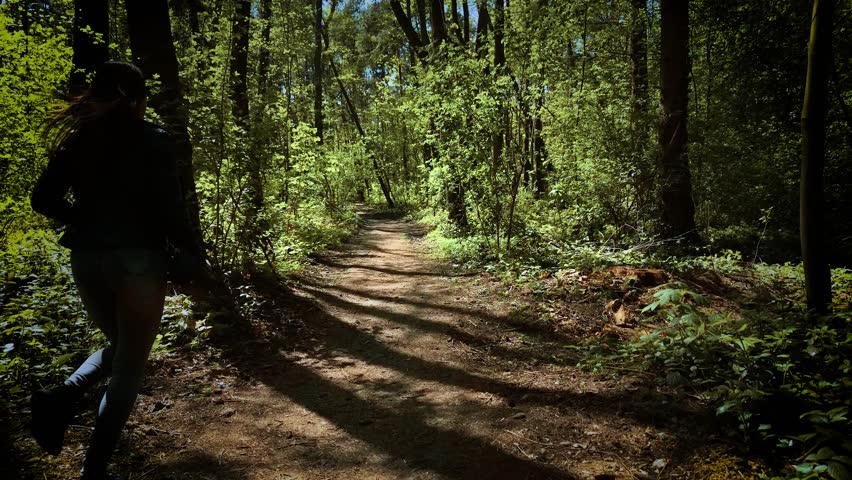 Horrified woman running and looking back in terror from serial killer. Scared female fleeing and glancing behind in panic from maniac. Frightened lady escaping and turning around in fear from murderer