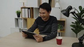 happy young man using digital tablet and wireless earbuds making video call in home office - Powered by Shutterstock - Get 15% off with code: PIKWIZARD15