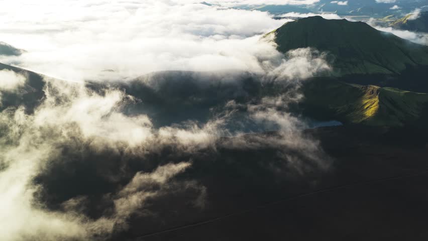 Aerial view of clouds rolling over the landscape of Hnausapollur Bláhylur View Point, creating a contrast between light and shadow, Rangárþing ytra, Iceland.