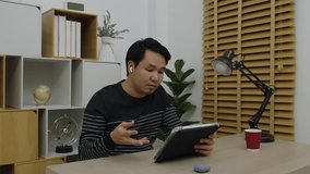 young man using digital tablet and wireless earbuds making video call in home office - Powered by Shutterstock - Get 15% off with code: PIKWIZARD15
