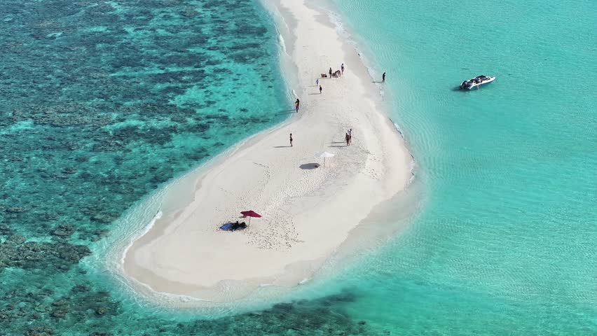 Aerial view of a pristine white sandbar surrounded by turquoise waters, dotted with people enjoying the sunny beach, Thoddoo, Alif Alif Atoll, Maldives.