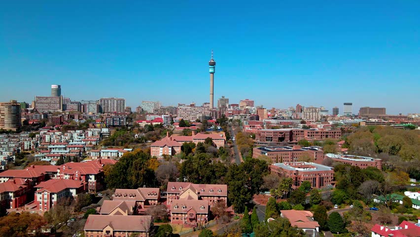 Aerial view of the vibrant Johannesburg skyline, featuring the iconic Hillbrow Tower piercing the clear blue sky, surrounded by buildings, Houghton Drive, South Africa.