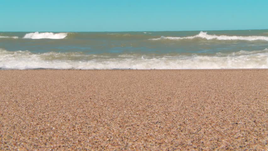 Close up of pebbled beach as Lake Michigan waves crash under clear sky, Indiana Dunes