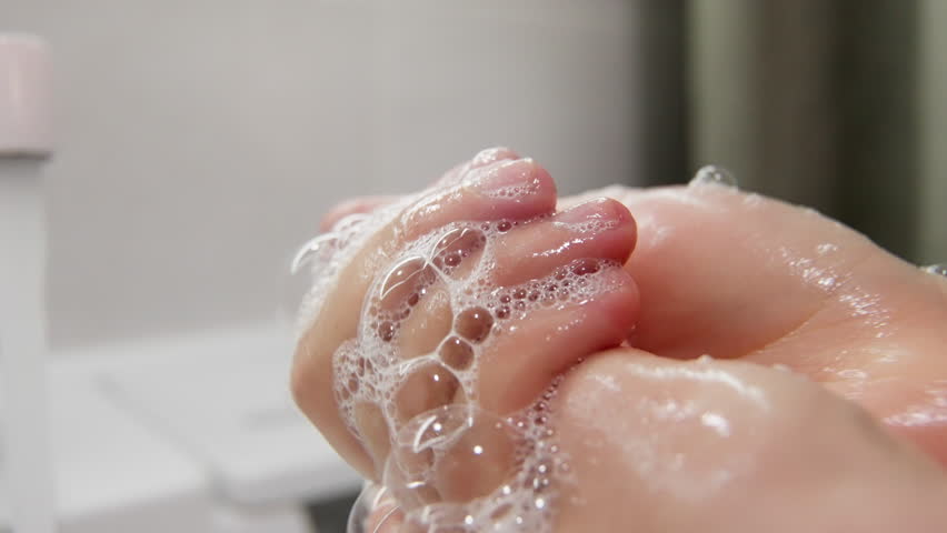Close-up sequence of hands being thoroughly washed with soap, lather, and bubbles, highlighting hygiene and cleanliness in a bathroom setting with foam and skin texture.