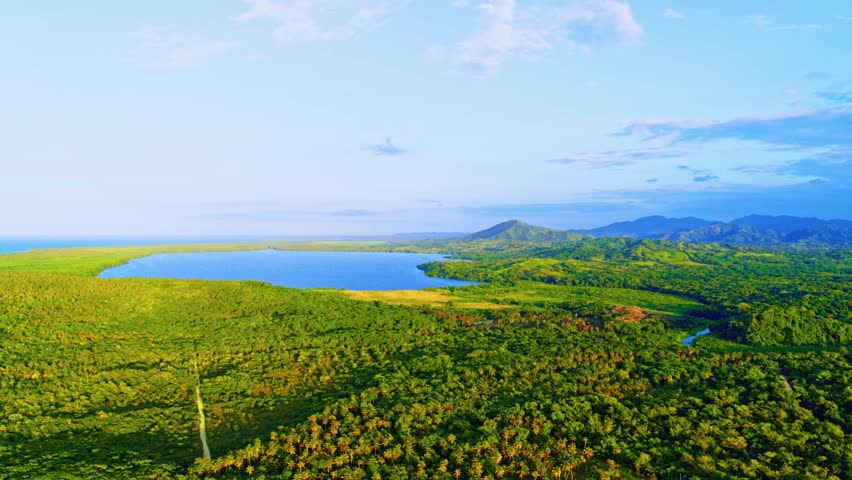 Summer mountain landscape in the Dominican Republic. Aerial panoramic view of green fields and meadows in summer. Mountain range against a blue sky with white clouds. Wildlife in Latin America.